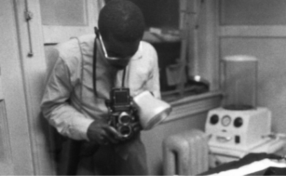 Black and white photo of Emmett Till's body being photographed at the funeral home