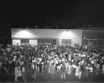 Black and white photo of a large crowd gathered outside the funeral home