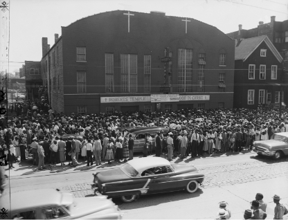 Black and white photo of thousands of people gathered outside the funeral home