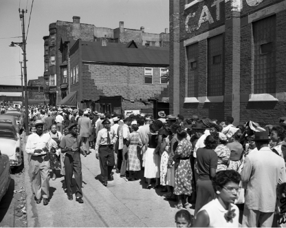 Black and white photo of people standing in line waiting to enter the church